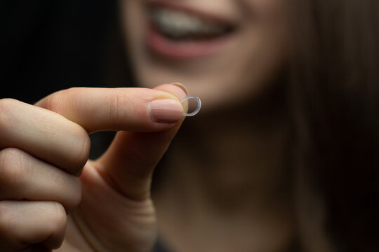 Young woman with braces is holding orthodontic rubber band.