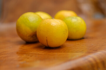 Baby oranges on edge of wooden table. All things yellow.