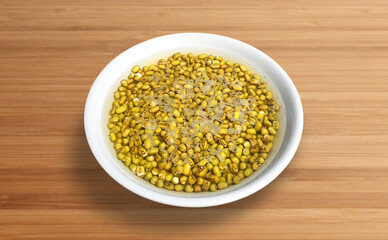 mung beans in a bowl of water isolated on a wooden background