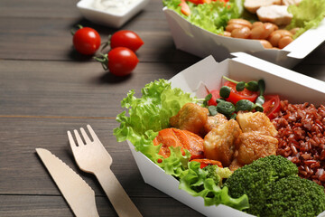 Delicious healthy meal in takeaway box on wooden table, closeup. Food delivery