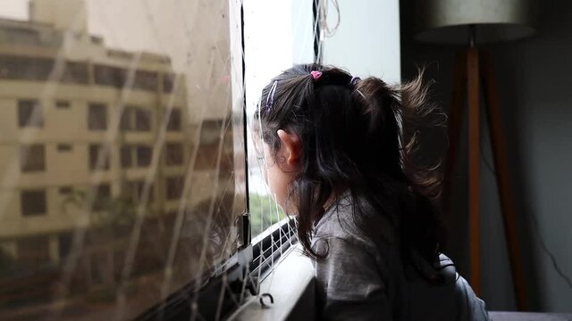 girl looks out the window in quarantine