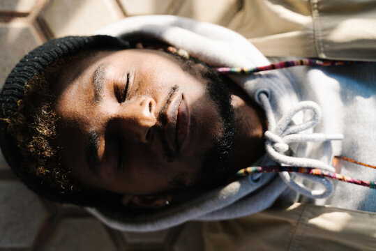 Young black guy sleeping on street in sunlight