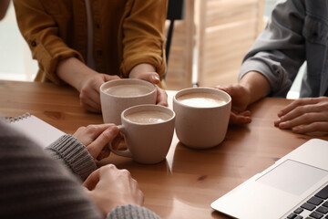 Women with cups of coffee at table in cafe, closeup