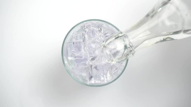 Vertiendo refresco de t&oacute;nica o bebida con gas en un vaso con hielos, vista desde arriba