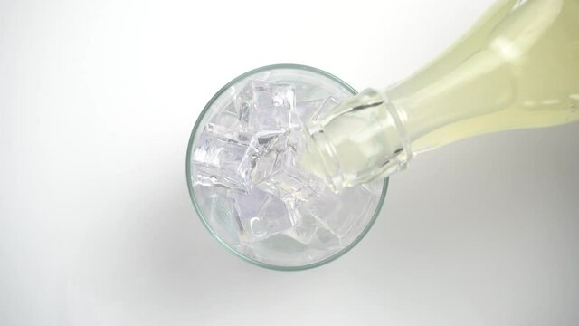 Vertiendo refresco de lim&oacute;n en un vaso con hielos, vista desde arriba