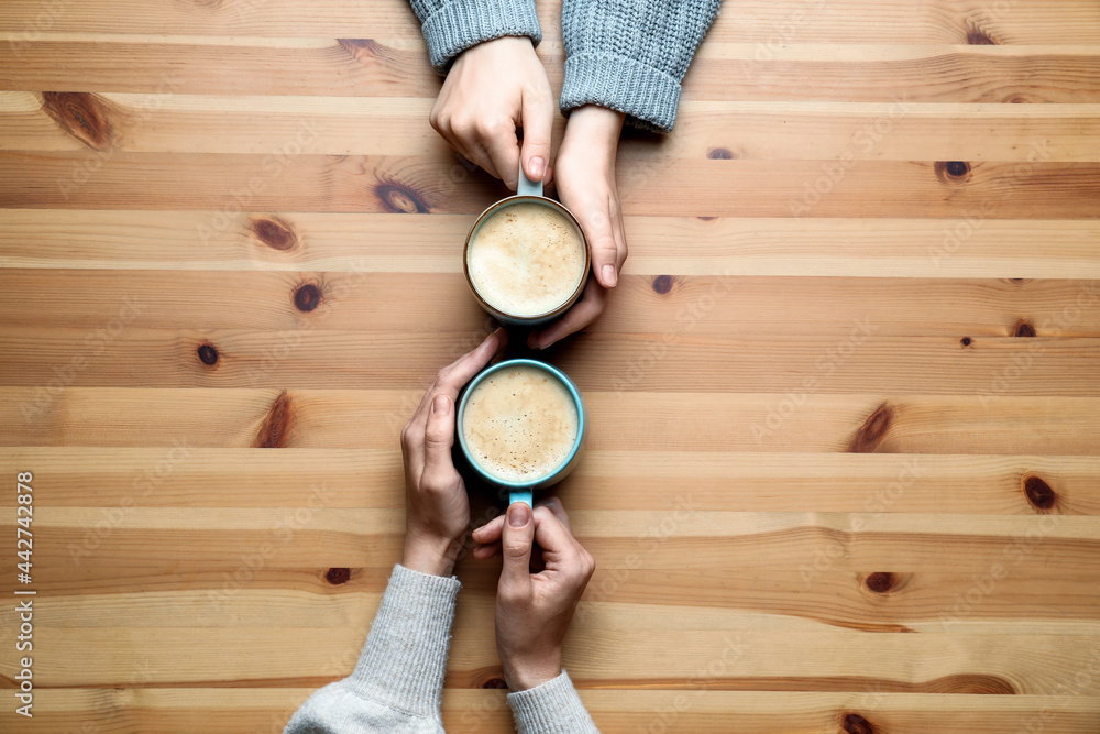 Sticker Women with cups of coffee at wooden table, top view