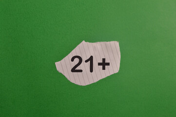 Torn paper with 21 plus sign isolated on green background