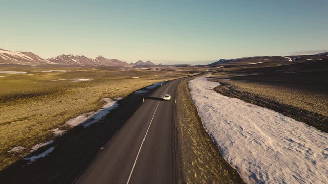 Aerial Shot of White Car Traveling on Road and Glimpse of Snow Capped Mountains