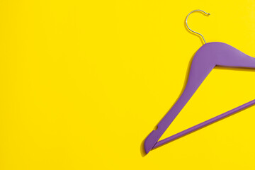 Purple wooden hanger on yellow background in close-up