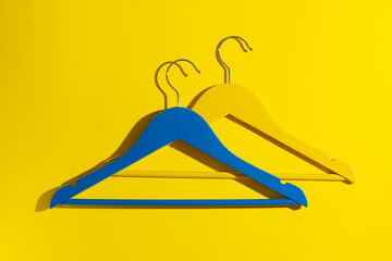 Yellow and blue wooden hanger on yellow background in close-up.