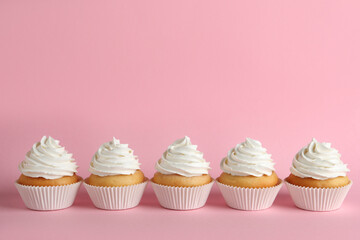 Delicious cupcakes with white cream on pink background. Space for text