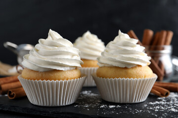 Delicious cupcakes with cream and cinnamon on slate board, closeup