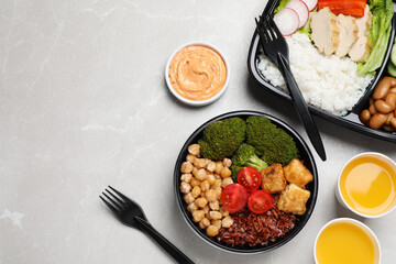 Healthy takeaway meals served with sauce and juice on light grey marble table, flat lay. Space for text