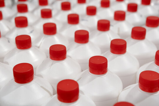 bottles cans plastic a rows of Professional household chemicals Liquid Refill in the hardware warehouse store. White Plastic canisters with red plastic cork cap.