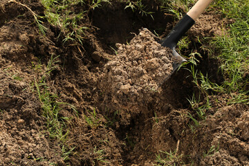 Digging soil with shovel outdoors, closeup. Gardening tool