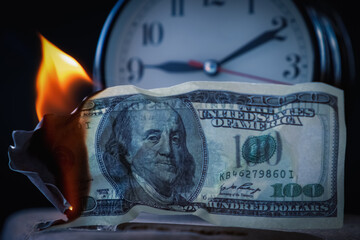Burning US Dollar bills against the clock as symbol of lost time and opportunities. Business...