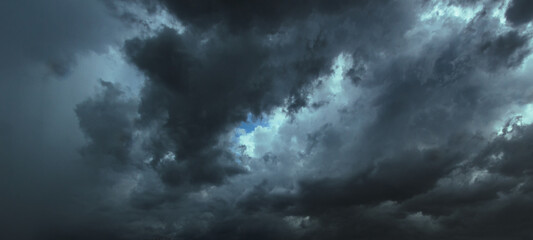 The dark sky had clouds gathered to the left and a strong storm before it rained.Bad or moody weather sky.