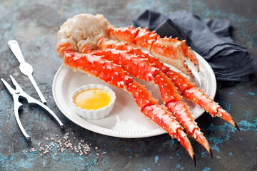 Red king crab legs with butter sauce on a plate, selective focus