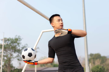 Sports and recreation concept a male goalkeeper standing in front of the goal throwing a ball as distributing in to a player after protecting the goal