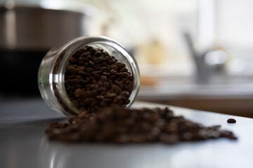 Bocal rempli de grains de café, renversé sur le plan de travail d'une cuisine moderne.