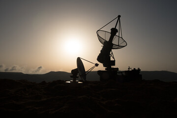 Space radar antenna on sunset. Silhouettes of satellite dishes or radio antennas against night sky....
