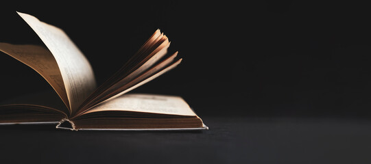 Open book, hardback books on a dark surface. Copy space.
