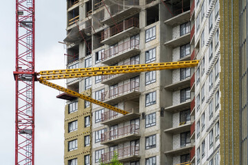 View of frame part of metallic crane machinery attachment at windows of new residential building construction site. Windows with sky reflection.