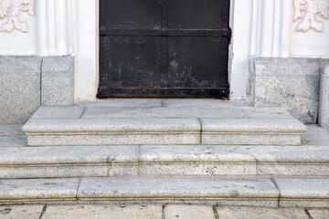 granite threshold at the entrance door made of black rust iron and white facade cladding of gray...