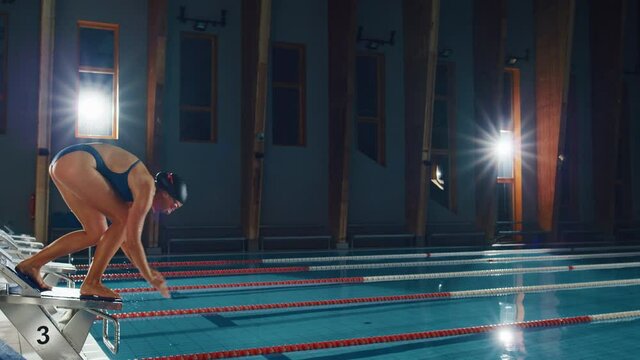 Beautiful Female Swimmer Diving in Swimming Pool. Professional Athlete Gracefully Jumps. Training Determined to Win Championship. Cinematic Light, Slow Motion with Stylish Colors, Artistic Aerial