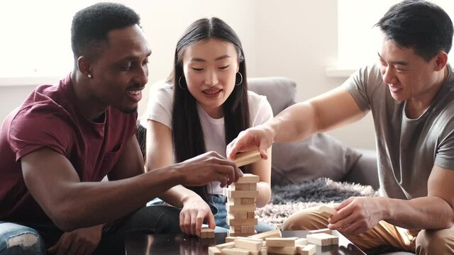 Young multi ethnic people playing jenga game indoors