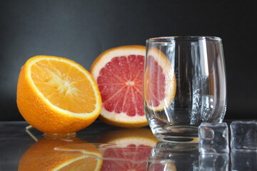 Cooking Lemonade Water in a glass of ice and fruit orange grapefruit on a black background. Summer drinks. A lemonade drink