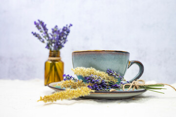 Obraz na płótnie Canvas Cup of hot aromatic tea with a bouquet of natural lavender on a gray background.