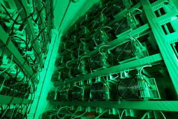 Bitcoin miners in large farm. ASIC mining equipment on stand racks mine cryptocurrency in steel...
