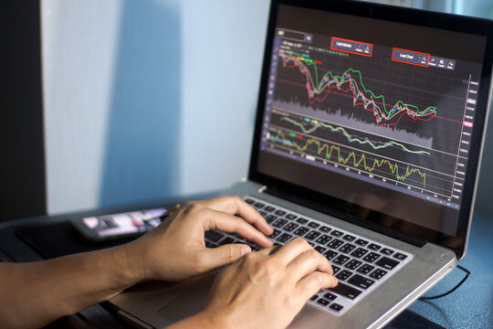 Man presses laptop keyboard to view stock market and analysis graph