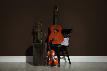 Set of different musical instruments near brown wall indoors