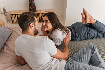 Man hugging cheerful girlfriend on bed