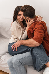 Man kissing girlfriend on couch at home