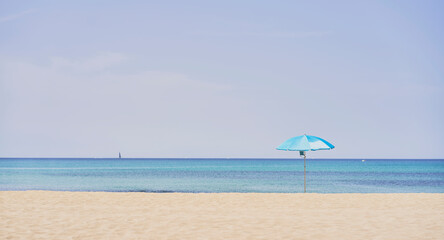Summer concept. Blue umbrella, beach and blue sea on a beautiful sunny day