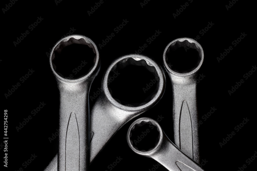 Wall mural Four steel closed end ring wrenches isolated on black background closeup