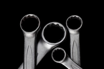 Four steel closed end ring wrenches isolated on black background closeup