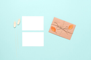 Blank business cards mockup, letter, autumn leaves and dry grass on pastel mint blue paper background. Autumn stationery still life. Top view, flat lay.