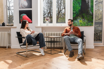 Obraz premium Smiling man with smartphone looking at girlfriend with book at home