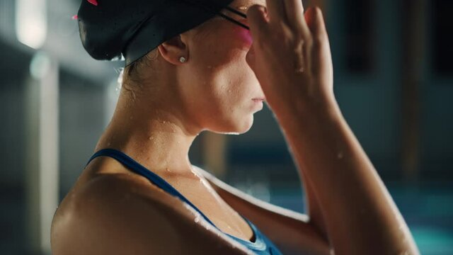 Beautiful Professional Female Swimmer in Swimming Pool, Wearing Cap, Looks Confidently Ahead, Puts on Glasses, Ready to Win the Championship, Set New World Record. Cinematic Close-up Profile Portrait