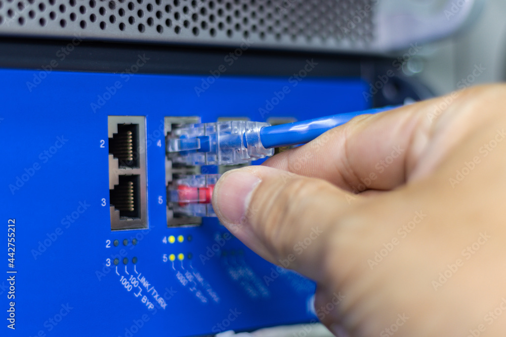 Poster hand of a man holding the network cables to connect the port of a switch to connect internet network