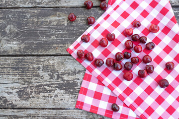 Obraz premium Red fresh cherries on wooden table with cell white red napkin top view, space for text. Ripe berries are delicious and contain healthy vitamins. Tasty Italy desert is obtained from fresh fruits