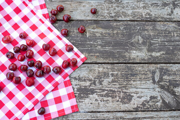 Red fresh cherries on wooden table with cell white red napkin top view, space for text. Ripe berries are delicious and contain healthy vitamins. Tasty Italy desert  is obtained from fresh fruits