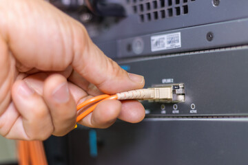 Hand of a man holding The network fiber optic cables to connect the port of a switch to connect internet network, concept Communication technology
