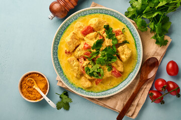 Chicken tikka masala. Traditional of indian cuisine curry and ingredients on dark background. Curry, lime, ginger, cilantro, chili, rice, herbs and spices. Top view with copy space.