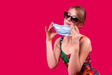 Travelling during the coronavirus outbreak girl with face mask and sunglasses is in a good mood smiling.