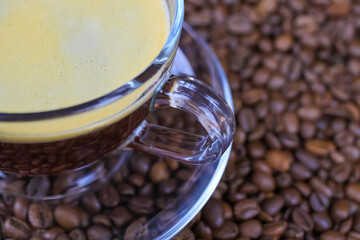 Closeup of isoalted transparent glass cup, saucer and handle with black coffee whitecap crema,...